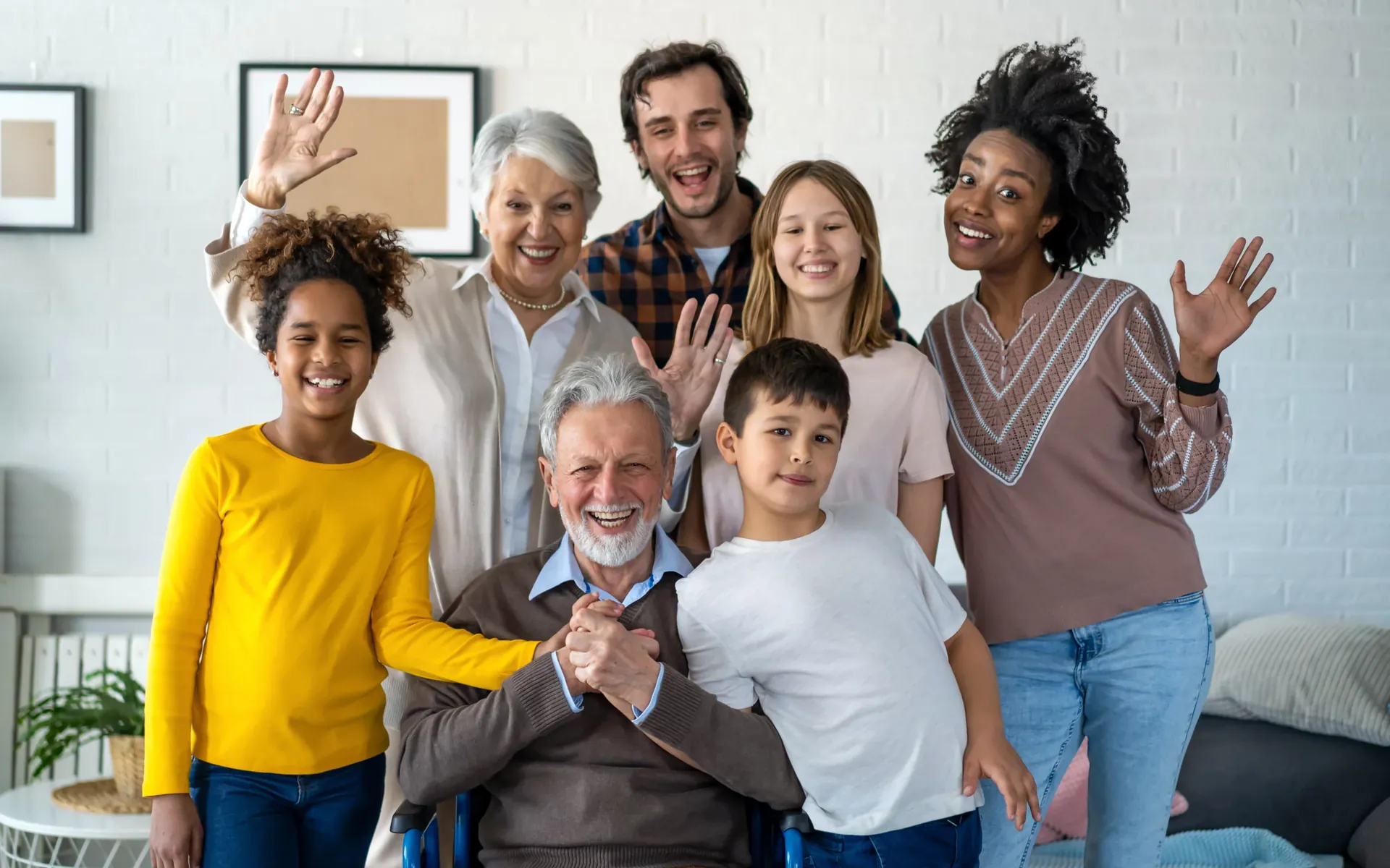 A multi-generation family waving at home