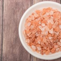Himalayan rock salt in a bowl over wooden background